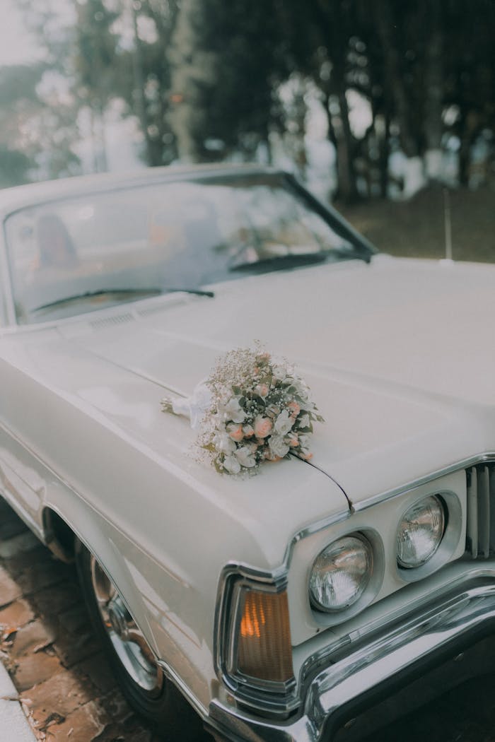 A classic car with a beautiful wedding bouquet on the hood, capturing a romantic vintage setting.